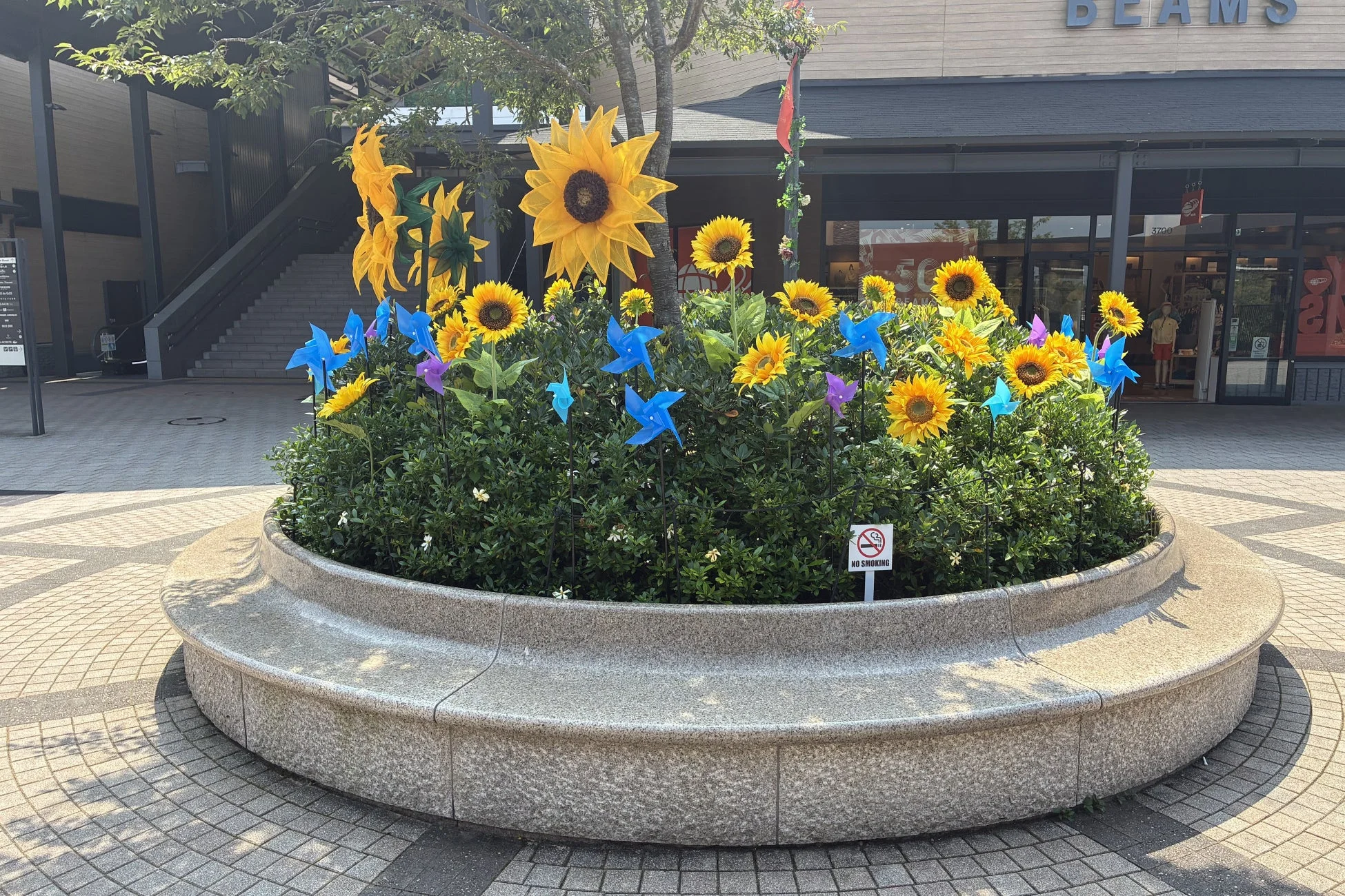 商業施設前の花壇に飾られたひまわりとカラフルな風車