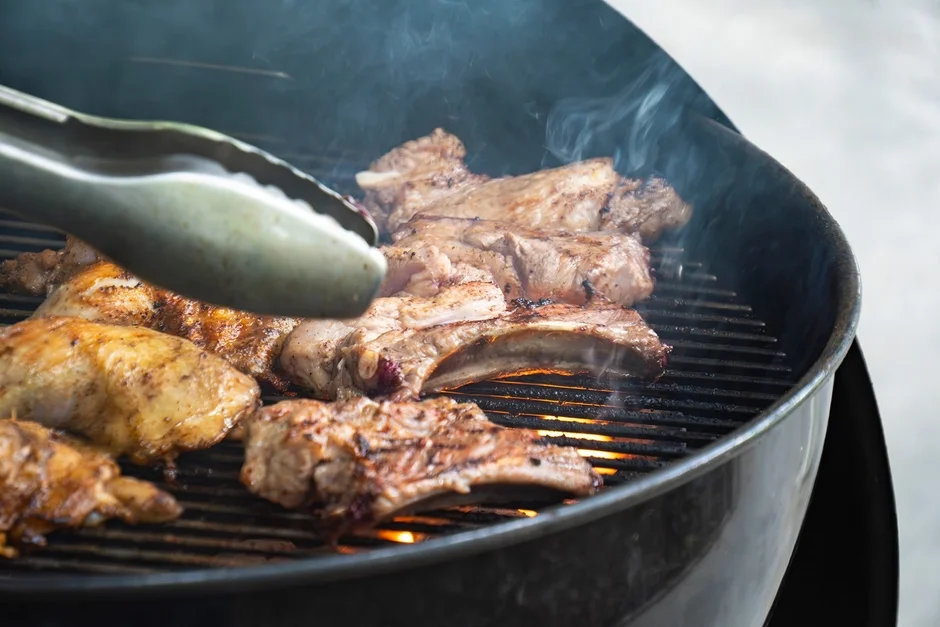 炭火で焼かれる骨付き肉と鶏肉