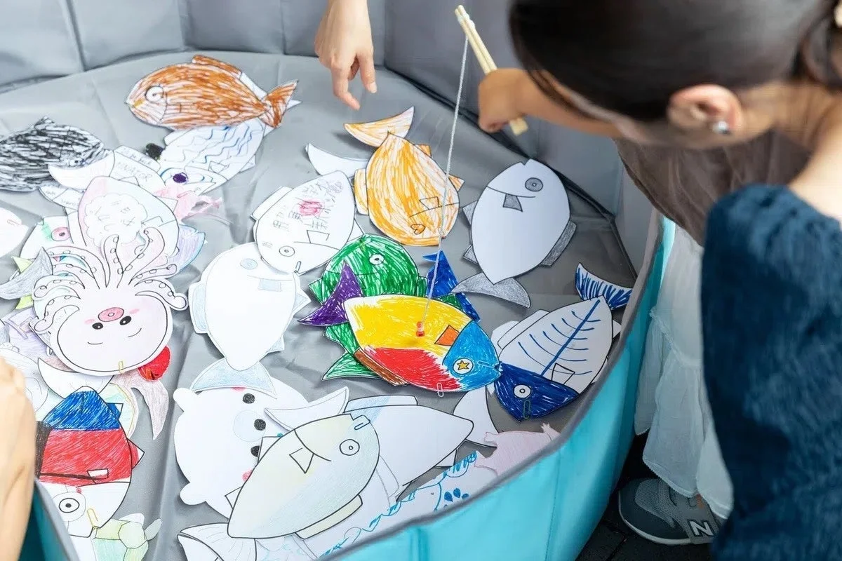 紙製のカラフルな魚を釣り上げるゲームを楽しむ様子です。