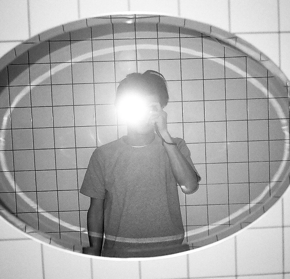鏡に映る人物がセルフィーを撮影している白黒写真