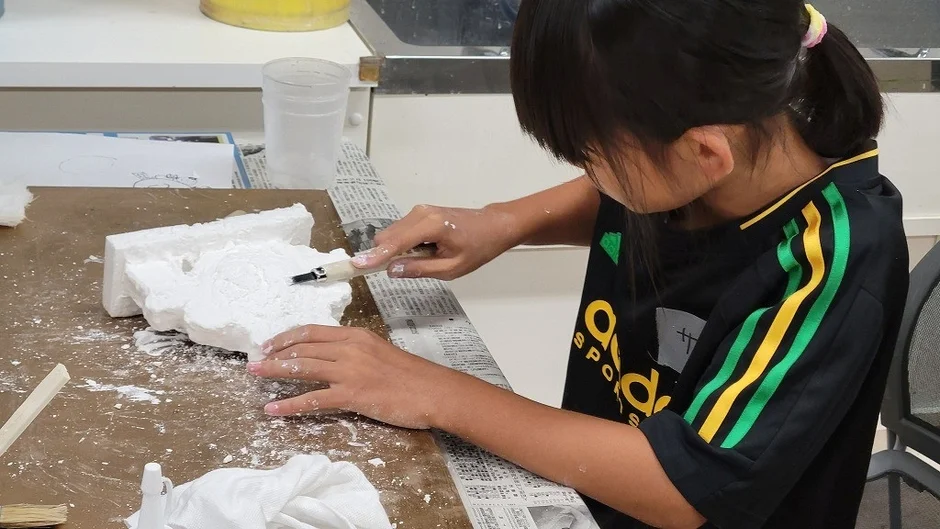 子供が白い素材を彫刻刀で削る工作に熱中している様子