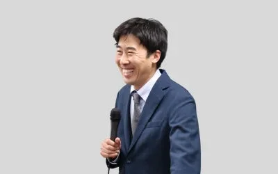 スーツ姿でマイクを持つ関内悠真講師