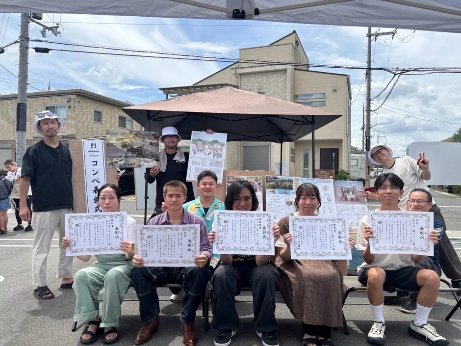 屋外で表彰状を手に記念撮影をする若者たち
