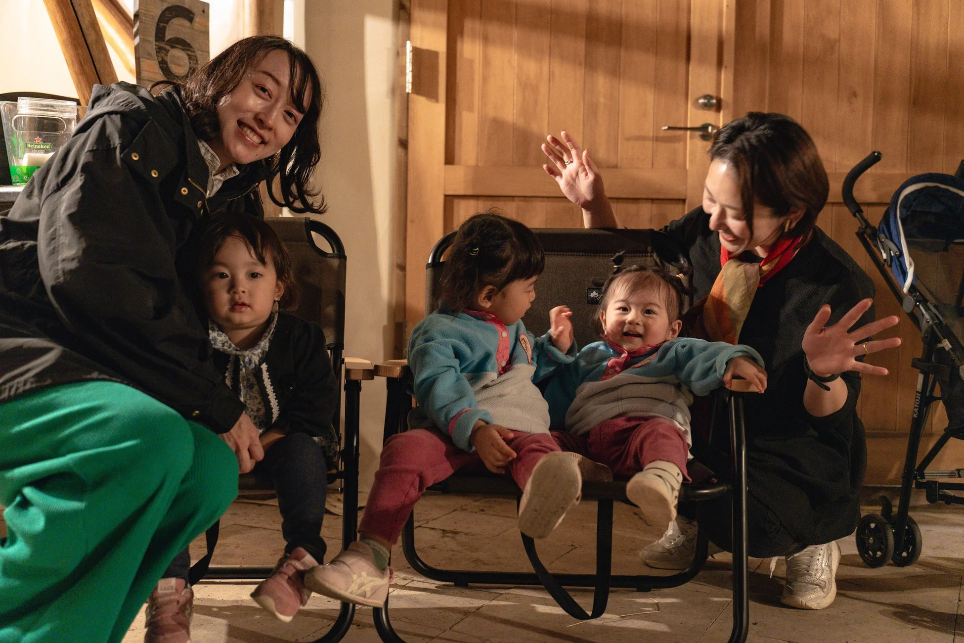 室内で数人の女性と幼い子供たちが集まり、笑顔で楽しそうに交流している様子