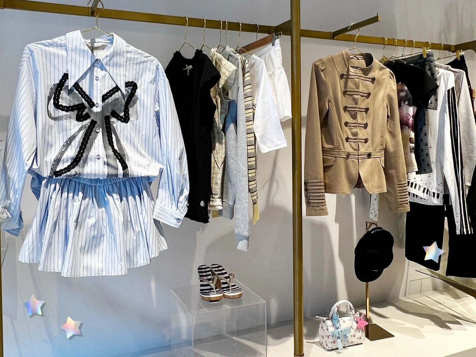 アパレルショップの店内ディスプレイで、様々な洋服がハンガーにかけられ、靴やバッグも陳列されている