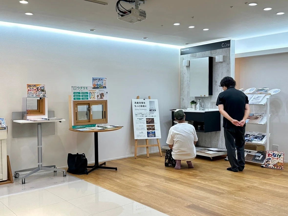 住宅設備ショールームでリフォーム製品を見る人々