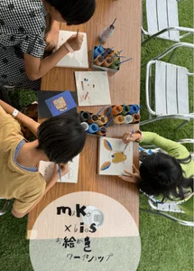 子供たちがテーブルを囲んで絵を描いているワークショップの様子です。様々な色の絵の具を使って、真剣に作品作りに取り組んでいます。