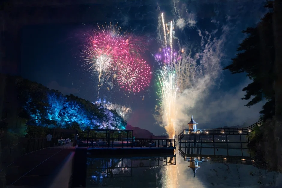 夜空に打ち上げられた色とりどりの花火が水面に美しく反射している夜景