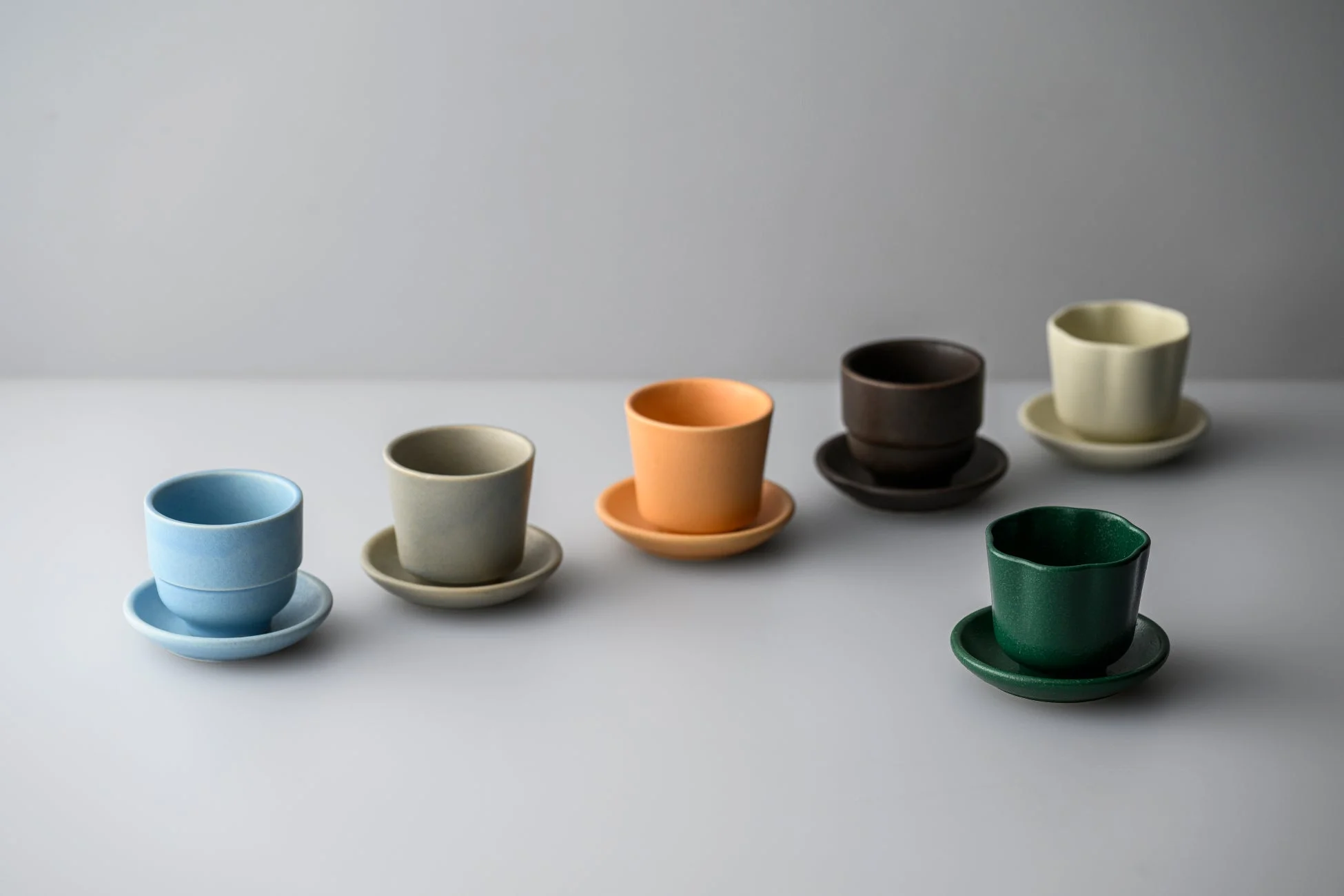様々な色の陶器のカップとソーサー