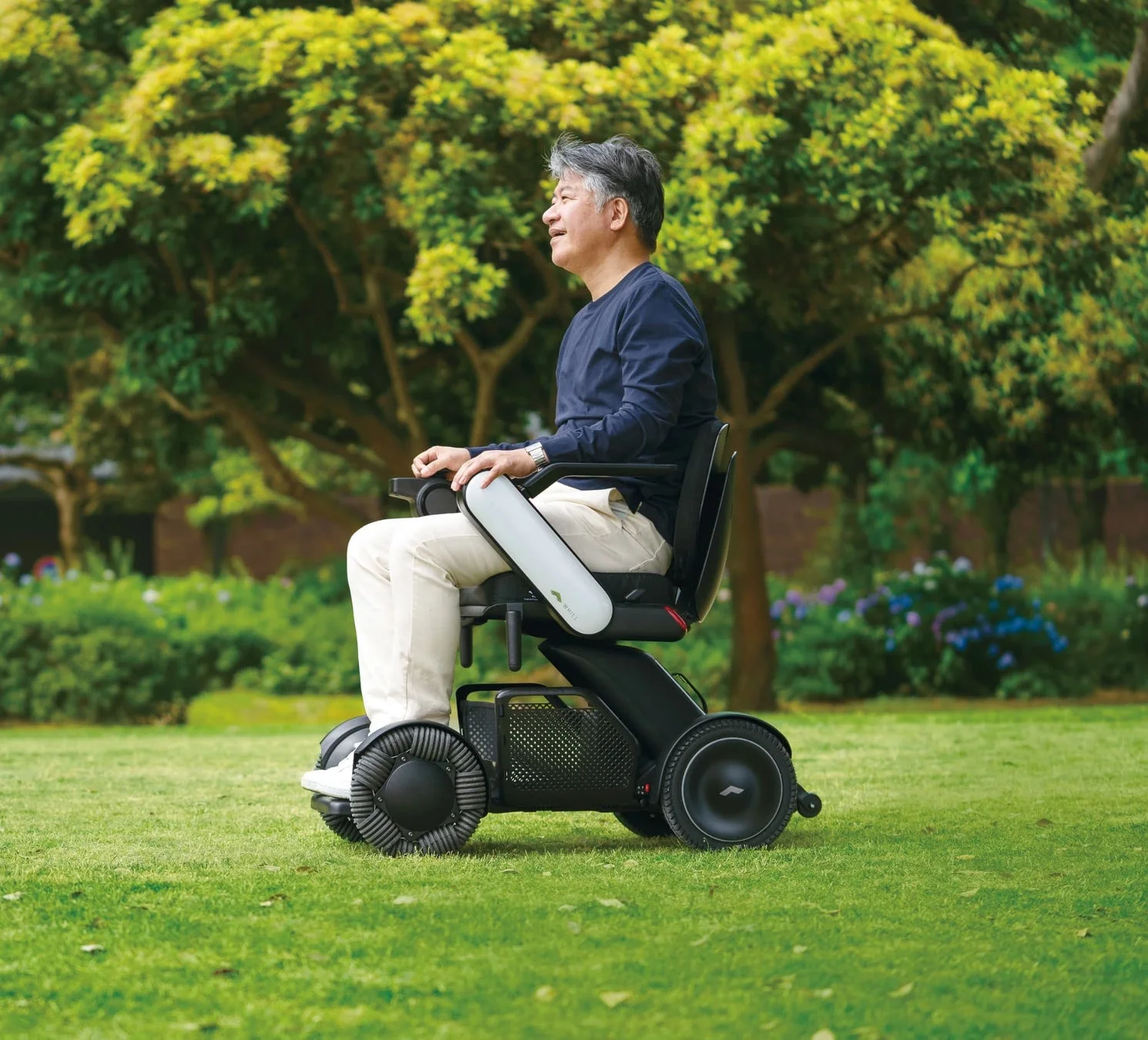 緑豊かな公園の芝生の上で電動車椅子に乗る男性
