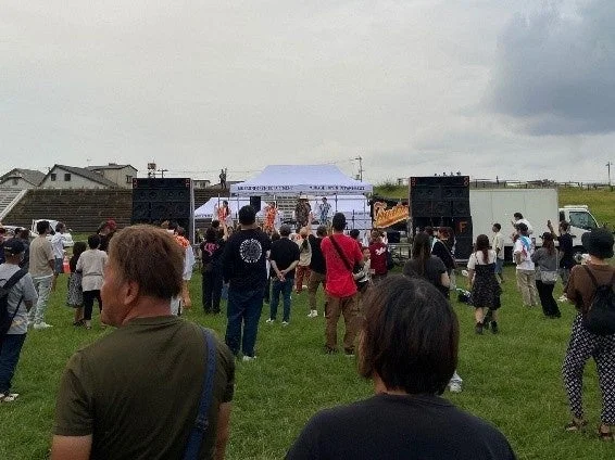 野外イベントのステージでパフォーマンスを楽しむ観客たち