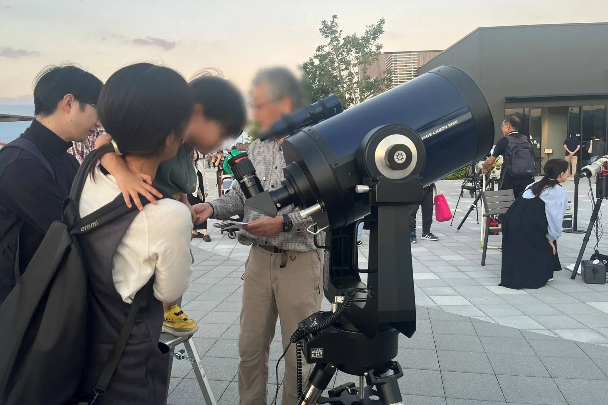 屋外で人々が大きな望遠鏡を囲んで天体観測をしている様子