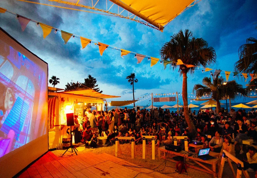 夕暮れのビーチで野外映画を鑑賞する人々