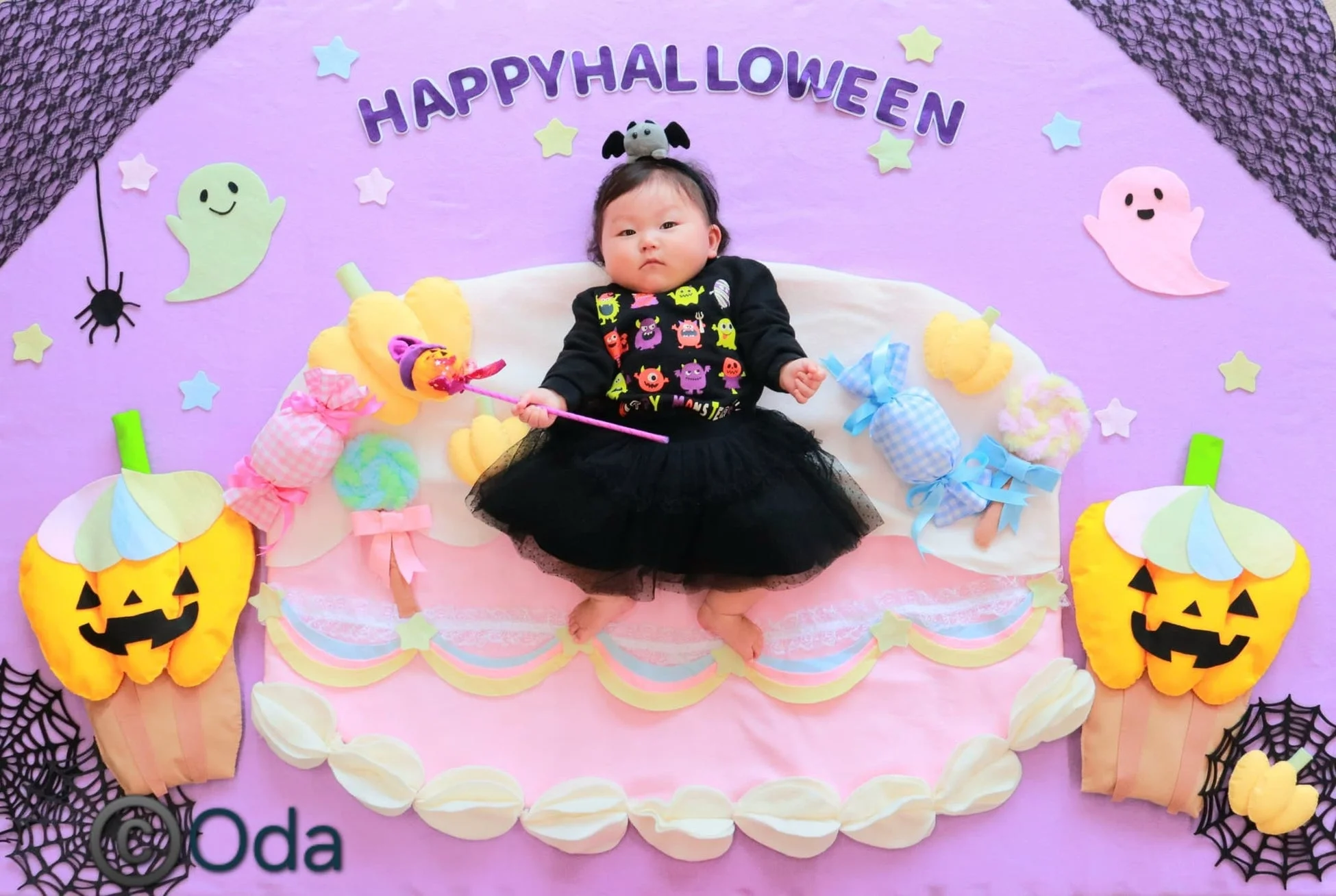 ハロウィンの飾り付けがされた背景で寝そべる赤ちゃん