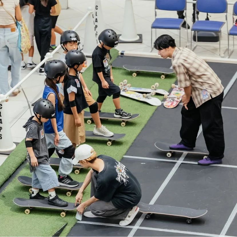 ヘルメットを着用した子供たちがスケートボードのレッスンを受けている様子