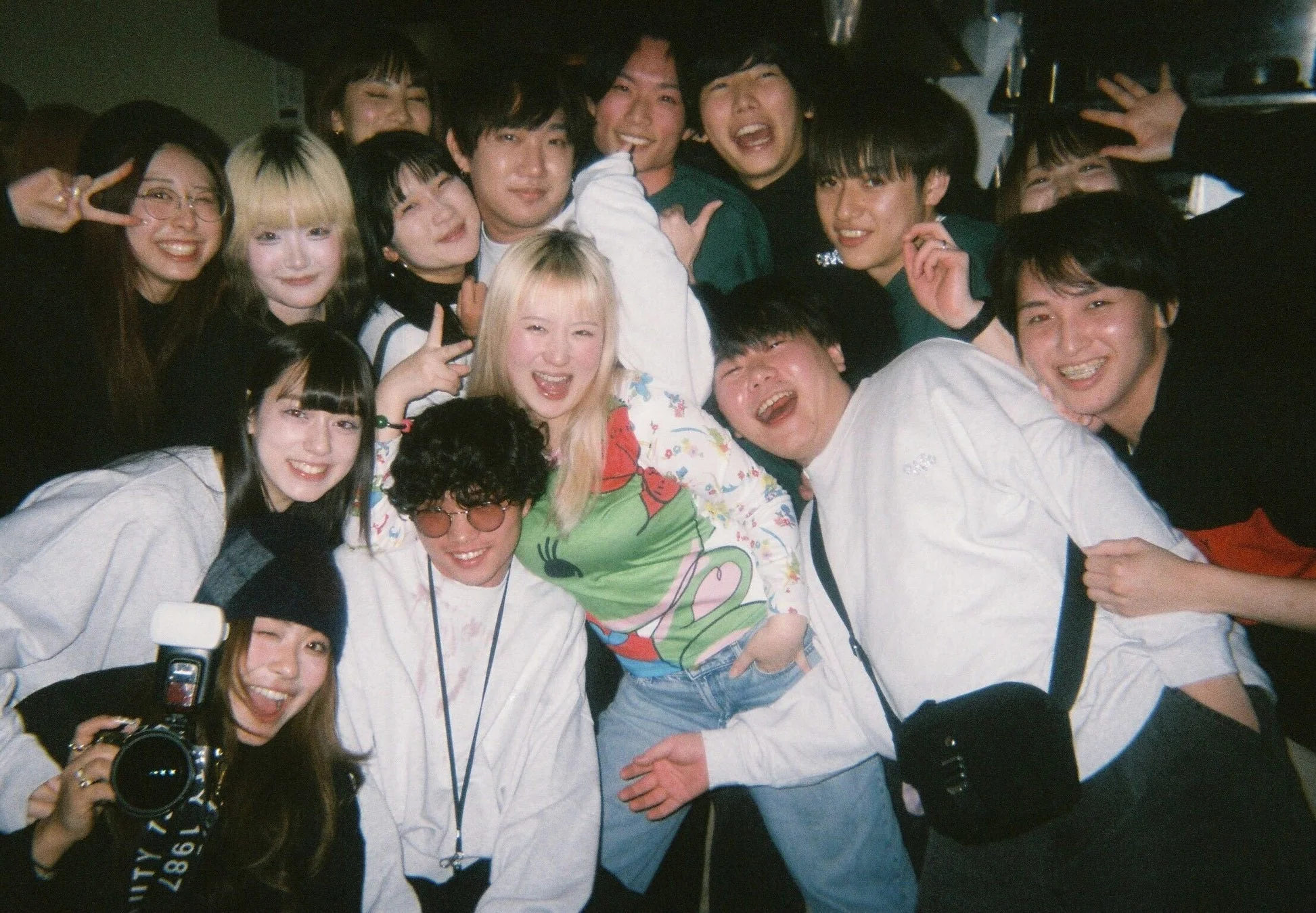 多くの若者が集まり、笑顔で楽しそうにポーズをとっている集合写真。友人同士の親密な関係と、活気に満ちた楽しい雰囲気が伝わる一枚。