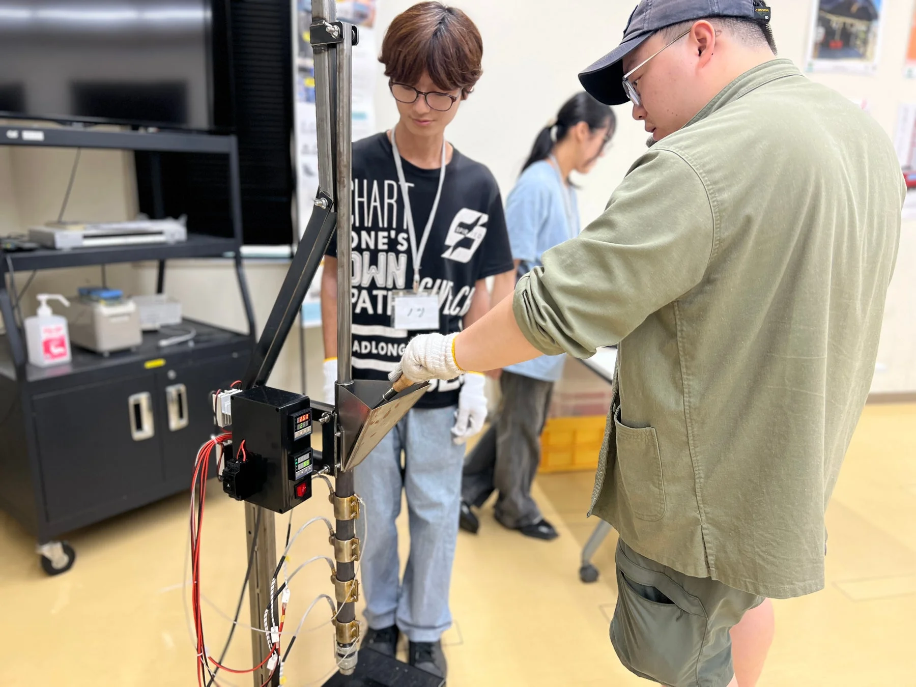 実験室または作業場で、二人の男性が複雑な装置を操作している様子