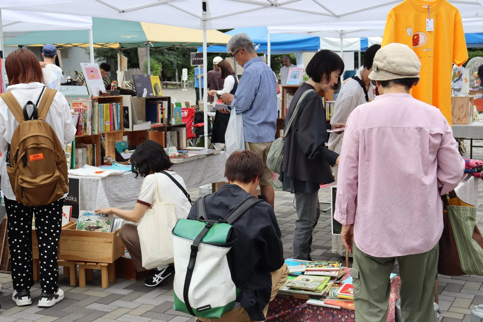 屋外の市場で本や商品を物色する人々